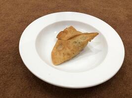 Fresh delicious crispy samosas on white Plate, top view, isolated photo