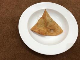 Fresh delicious crispy samosas on white Plate, top view, isolated photo