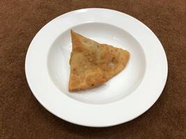 Fresh delicious crispy samosas on white Plate, top view, isolated photo