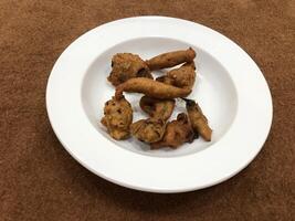 Mirchi pakora or Mirchi bhajji served in a white plate, a famous midday snack in india, served over a rustic wooden background, selective focus photo