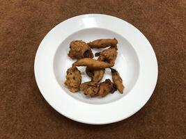 Mirchi pakora or Mirchi bhajji served in a white plate, a famous midday snack in india, served over a rustic wooden background, selective focus photo