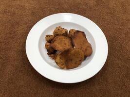 Mirchi pakora or Mirchi bhajji served in a white plate, a famous midday snack in india, served over a rustic wooden background, selective focus photo