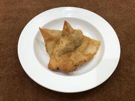 Fresco delicioso crujiente dos Samosas en blanco lámina, parte superior vista, aislado foto