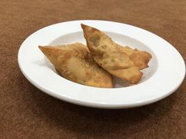 Fresco delicioso crujiente dos Samosas en blanco lámina, parte superior vista, aislado foto