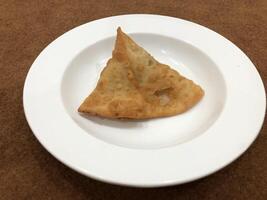 Fresh delicious crispy samosas on white Plate, top view, isolated photo