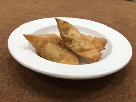 Fresco delicioso crujiente dos Samosas en blanco lámina, parte superior vista, aislado foto