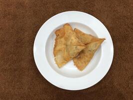 Fresco delicioso crujiente dos Samosas en blanco lámina, parte superior vista, aislado foto