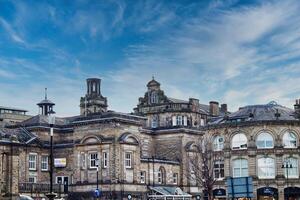 Classic European architecture under a dynamic sky with wispy clouds, showcasing historic buildings with intricate facades in an urban setting in Harrogate, North Yorkshire. photo