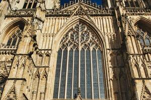 gótico arquitectura detalle de un catedral fachada, presentando un grande manchado vaso ventana y florido Roca tallas debajo claro cielo en york, norte yorkshire, Inglaterra. foto