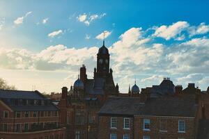 Vintage European architecture with a clock tower against a backdrop of a dramatic sky with fluffy clouds, capturing the essence of a historic town at sunset in York, North Yorkshire, England. photo