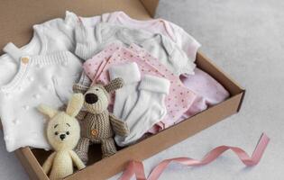 Baby and child clothes and knitted toys in carton box. photo