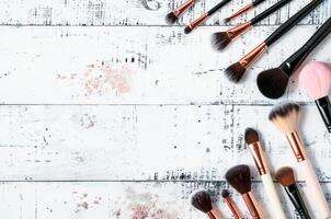Assorted Makeup Brushes Arranged on a Distressed Wooden Surface With Paint Splatters photo