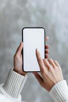 Person Holding a Smartphone With a Blank Screen While Sitting on a Cozy Blanket photo