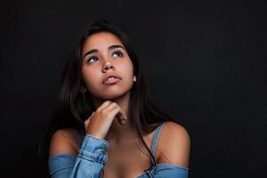 Thoughtful Young Woman Posing Against Dark Background photo