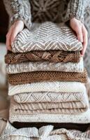 Cozy Hands Resting on a Pile of Warm Knitted Sweaters photo