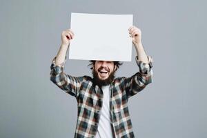 Smiling Young Man Holding a Blank Sign Aloft Against a Gray Background photo