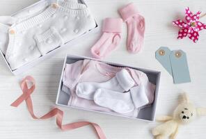 Box with baby stuff and accessories for newborn on white wooden background. photo