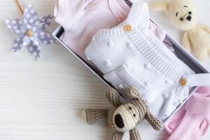 Baby clothes, knitted toys, socks in box. photo