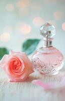 elegante perfume botella metido siguiente a un floreciente rosado Rosa en un suave borroso antecedentes foto