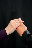 Wedding ring photo shoot concept a man wearing a formal black suit and purple tie and woman with purple suit is holding a wedding ring