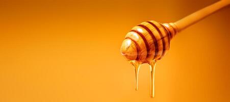 Honey dripping from wooden honey dipper over yellow background. Sweet bee product for your design with copyspace. photo