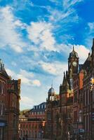 Vintage European architecture with a prominent clock tower under a vibrant blue sky with wispy clouds, capturing the essence of historic urban charm in York, North Yorkshire, England. photo