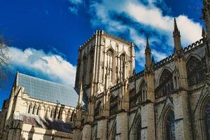 Majestic Gothic cathedral against a blue sky with fluffy clouds, showcasing intricate architecture and historical grandeur in York, North Yorkshire, England. photo