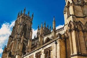 Majestic Gothic cathedral against a blue sky with clouds, showcasing intricate architecture and historical religious significance in York, North Yorkshire, England. photo