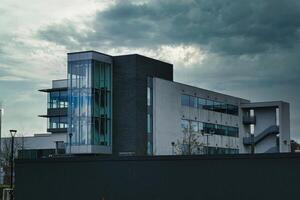 Modern office building against a dramatic cloudy sky, showcasing contemporary architecture with a mix of glass and concrete elements. photo