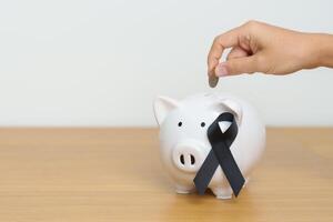 melanoma y piel mayo cáncer mes, negro cinta con cerdito banco para apoyo enfermedad vida. salud, donación, caridad, campaña, dinero ahorro, fondo y mundo cáncer día concepto foto