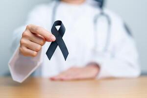 Melanoma and skin cancer, Vaccine injury awareness month and rest in peace concepts. doctor holding black Ribbon photo