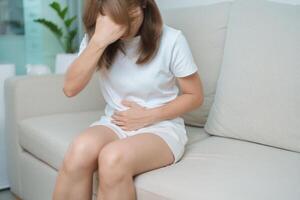 woman having abdomen ache due to Stomach pain, digestion with constipation or Diarrhea from food poisoning, female problem and Endometriosis, Hysterectomy, Stomachache and Menstrual on sofa at home photo