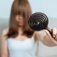 pelo pérdida problema, que se está quedando calvo , belleza tratos y salud cuidado conceptos asiático mujer participación participación peine con pelo pérdida, joven hembra sostener cepillo para el pelo y cepillado con otoño pelo desde cuero cabelludo foto