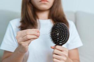 Hair loss problem, Balding , Beauty treatments and health care concepts asian woman holding holding comb with hair loss, young female hold hairbrush and brushing with fall hair from scalp photo