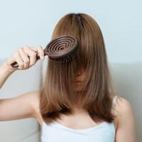 pelo cuidado y diario rutina conceptos. asiático mujer participación participación peine y pelo cepillado en el mañana, joven hembra sostener cepillo para el pelo con largo Derecho pelo a hogar foto