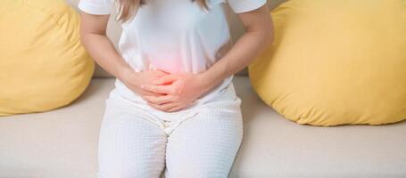 woman having abdomen ache due to Stomach pain, digestion with constipation or Diarrhea from food poisoning, female problem and Endometriosis, Hysterectomy, Stomachache and Menstrual on sofa at home photo