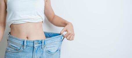 joven Delgado hembra vistiendo grande o demasiado grande vaqueros, mujer espectáculo sano forma después peso pérdida. haciendo dieta, ejercicio, cuerpo ajuste y liposuccion cirugía concepto foto