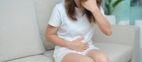 woman having abdomen ache due to Stomach pain, digestion with constipation or Diarrhea from food poisoning, female problem and Endometriosis, Hysterectomy, Stomachache and Menstrual on sofa at home photo