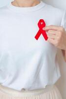 mujer con rojo cinta para diciembre mundo SIDA día, adquirido inmune deficiencia síndrome, múltiple mieloma cáncer conciencia mes y nacional rojo cinta semana. cuidado de la salud y mundo cáncer día concepto foto