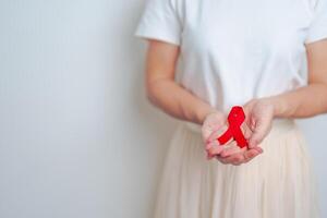 mujer con rojo cinta para diciembre mundo SIDA día, adquirido inmune deficiencia síndrome, múltiple mieloma cáncer conciencia mes y nacional rojo cinta semana. cuidado de la salud y mundo cáncer día concepto foto