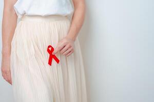 mujer con rojo cinta para diciembre mundo SIDA día, adquirido inmune deficiencia síndrome, sexual transmitido enfermedades, sífilis, chancroide, genital herpes, gonorrea, cuidado de la salud y mundo cáncer día foto