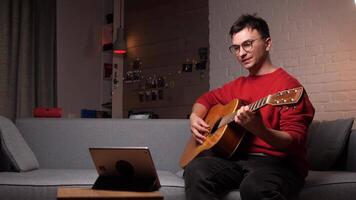 man learning guitar in online music class with distant teacher on tablet video