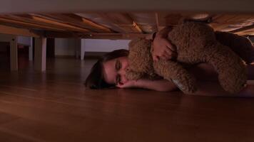 a little girl frightened by lightning hugs a teddy bear under the bed video