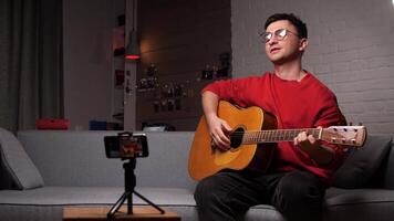 joven hombre grabación guitarra en móvil computadora contenido para en línea Blog video