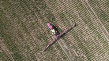 aéreo parte superior ver rojo tractor rociador trabajos un campo de joven maíz en un seco año video