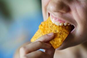 Crop unrecognizable teenage girl biting delicious Mexican tortilla chips photo