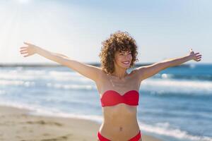 Happy woman with ginger hair standing in bikini on beach photo