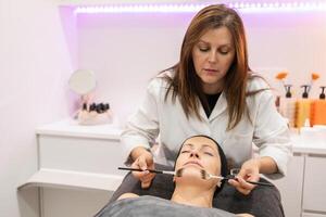 Cosmetician doing facial cleansing for client in beauty center photo