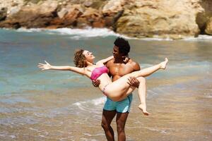 diverso Pareja teniendo divertido en playa en luz foto