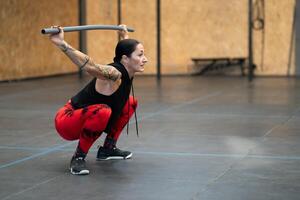 Mature woman squatting with a bar in a gym photo